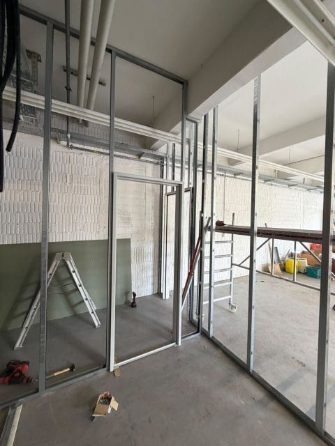 Metallständerwand mit ausgesparter Türöffnung, im Hintergrund die Halle