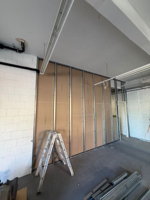 Metallständer vor einer Wand aus braunen Platten, davor eine Bockleiter